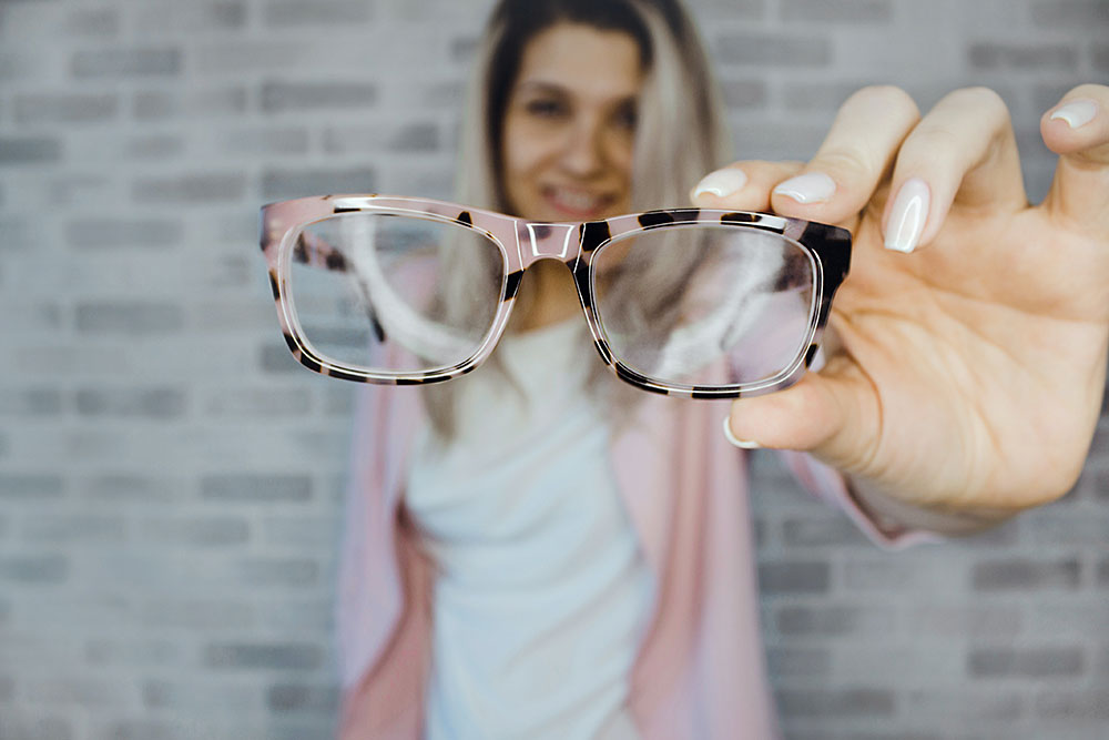 Woman holding pair of glasses